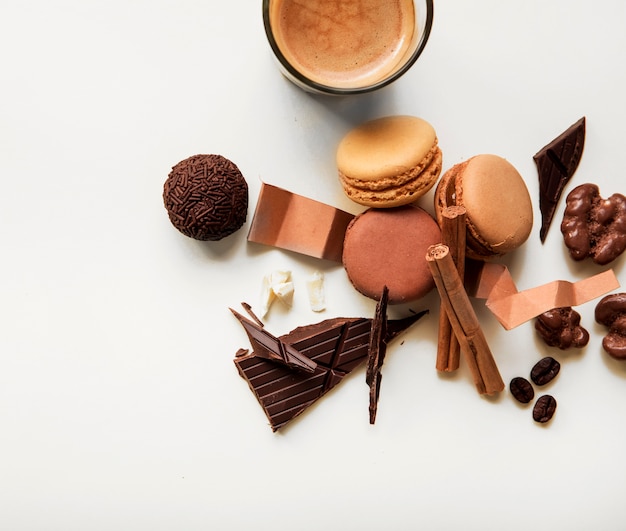 Verre à café; macarons et morceau de chocolat avec des ingrédients sur fond blanc Photo gratuit