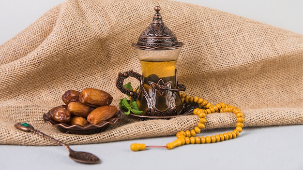 Verre à thé avec fruits de dattes et perles de chapelet Photo gratuit
