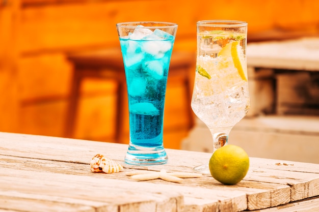 Verres de boissons à la menthe bleue et citron vert avec étoile de mer à la table en bois Photo gratuit