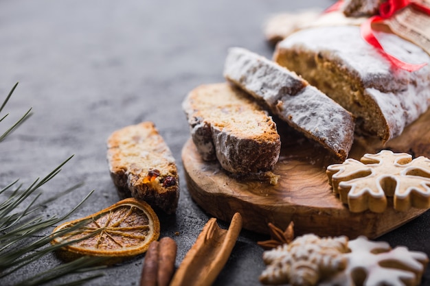 Volé. Tranches De Dessert De Noël Maison Tranché Avec Des Baies Séchées Et Des Noix Sur Une Table Rustique En Pierre Avec De La Cannelle, Des Tranches D'orange, Des Branches D'arbres De Noël, Du Pain D'épices, Une Mise Au Point Sélective Photo Premium