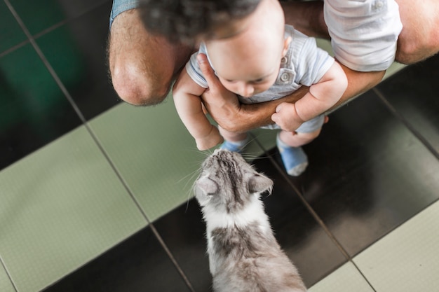 Une vue aérienne du père tenant son bébé devant un chat Photo gratuit