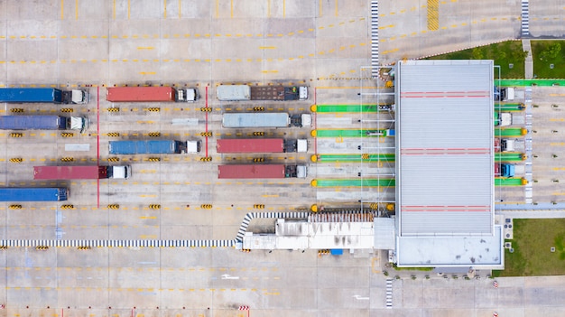 Vue aérienne de gros camions porte-conteneurs entrant avec un conteneur de marchandises par la porte d'entrée principale du port industriel. Photo Premium