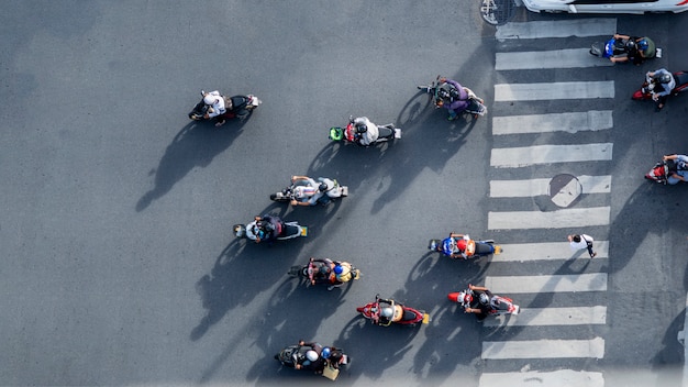 Vue aérienne de haut sur les motards flous conduisent les motos pour passer le passage pour piétons sur la route avec les panneaux de signalisation de circulation dans la rue. Photo Premium