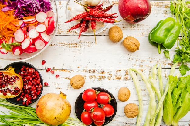 Une vue aérienne de tomates cerises; piments rouges; oignon de printemps; ail; salade; persil; grenade mûre; rougeâtre et noyer Photo gratuit