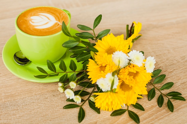 Vue d'angle élevé de tasse à café art latte avec une fleur fraîche sur un fond texturé en bois Photo gratuit