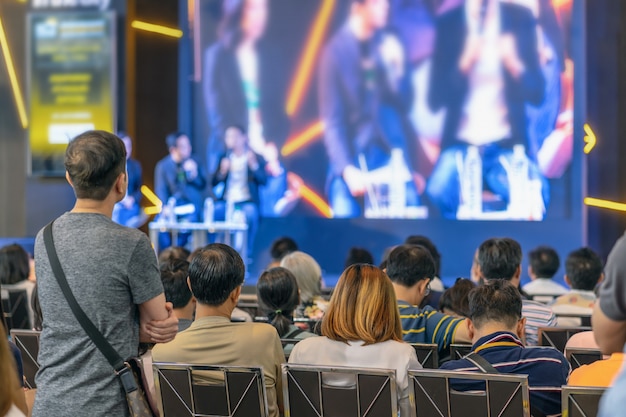 Vue arrière de l'audience à l'écoute des intervenants sur la scène dans la salle de conférence ou une réunion de séminaire Photo Premium