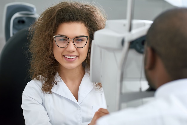 Vue arrière du jeune homme assis pendant la vérification de la vue avec un oculiste qualifié. Photo Premium