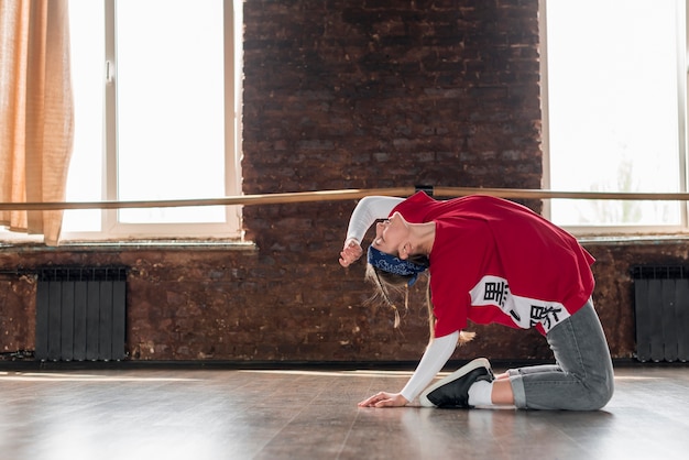 Vue de côté d'une danseuse faisant la pratique dans le studio de danse Photo gratuit