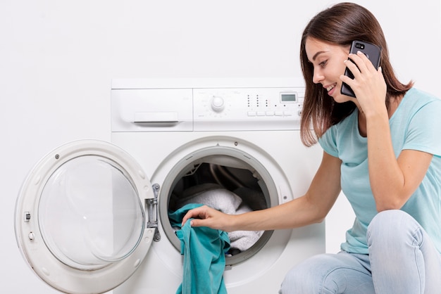 Vue côté, femme, parler, téléphone, dans, buanderie Photo gratuit