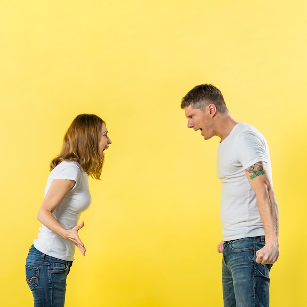 Vue côté, de, jeune couple, gronder, à, autre, sur, jaune, fond Photo gratuit