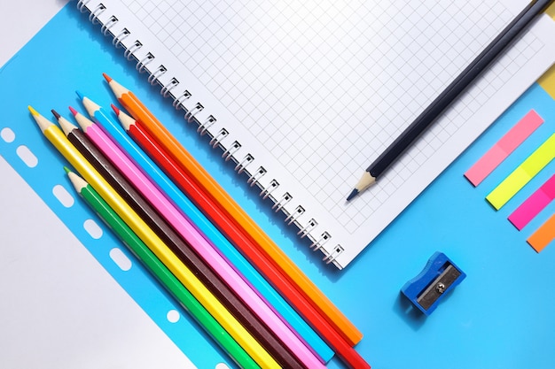 Vue de dessus sur un cahier, crayons, taille-crayon sur fond bleu. concept de retour à l'école Photo Premium