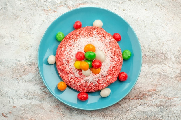 Vue De Dessus Un Delicieux Gateau Rose Avec Des Bonbons Colores A L Interieur De La Plaque Sur Un Dessert De Gateau A Tarte Aux Couleurs De Bonbons Arc En Ciel De Surface Blanche