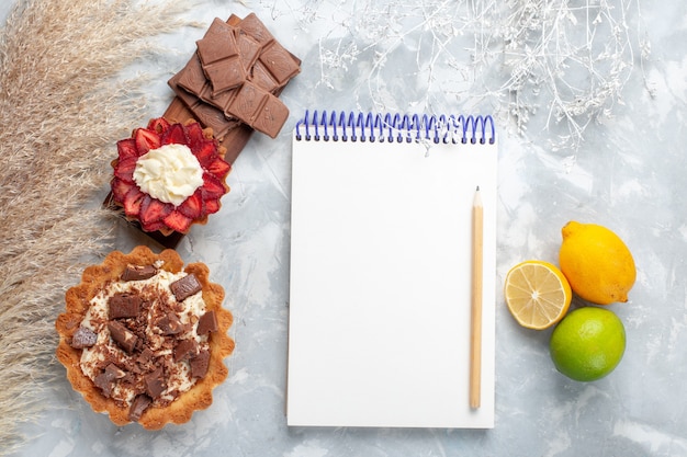 Vue De Dessus De Delicieux Gateaux Cremeux Avec Des Barres De Chocolat Et Du Citron Sur Le Bureau Blanc Gateau Biscuit Sucre Sucre Cuire Photo Gratuite