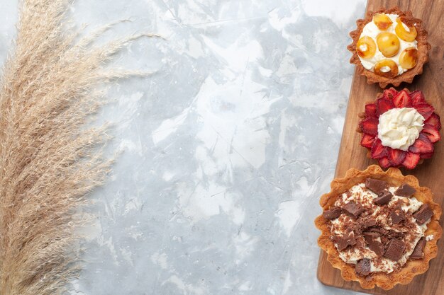 Vue De Dessus Differents Gateaux Cremeux Au Chocolat Et Fruits Sur Gateau De Bureau Blanc Cuire Au Four Biscuit Sucre Sucre Photo Gratuite