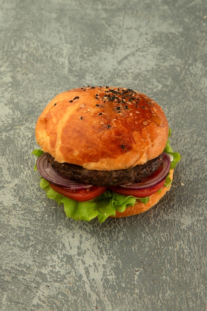 Vue de dessus du burger de boeuf avec laitue, tomate, oignon au fond gris uni Photo gratuit