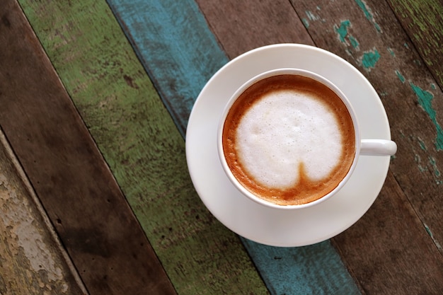 Vue de dessus du café chaud avec art de latte en forme de coeur dans une tasse blanche servie sur une table en bois de style rustique Photo Premium