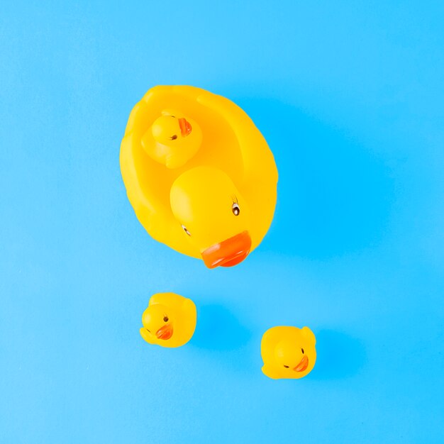 Une vue de dessus du canard en caoutchouc jaune mignon avec des canetons sur fond bleu Photo gratuit