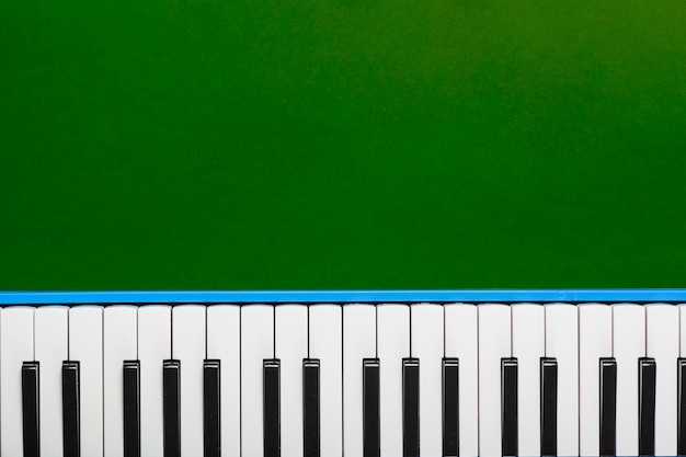 Vue de dessus du clavier noir et blanc de piano classique sur fond vert Photo gratuit