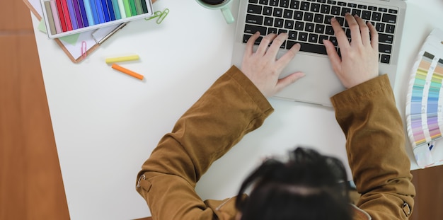 Vue de dessus du graphiste femme en tapant sur le clavier d'ordinateur portable Photo Premium