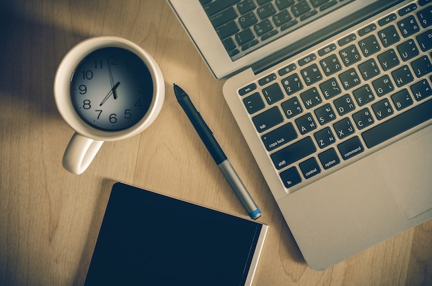 Vue de dessus du portable, du bloc-notes et de la tasse à café indiquant l'heure Photo Premium