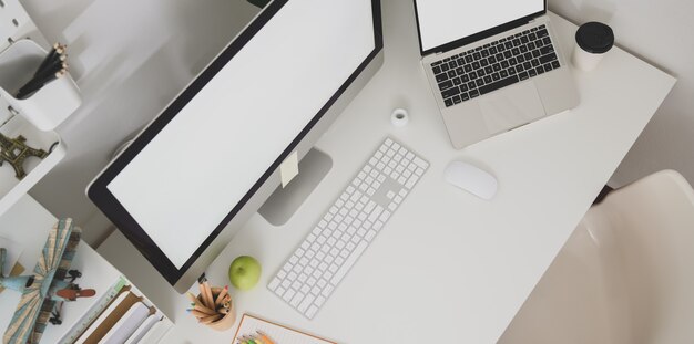 Vue de dessus du poste de graphiste avec un ordinateur portable à écran blanc Photo Premium
