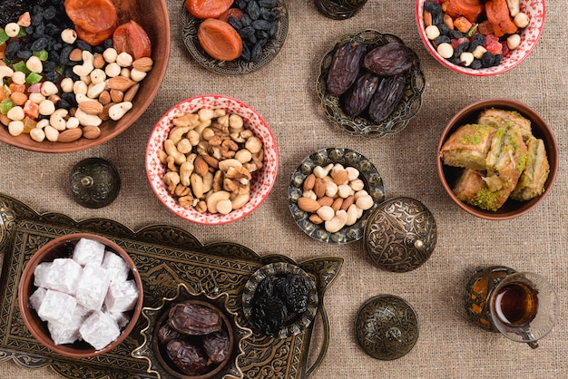Une vue de dessus du thé turc; rendez-vous; lukum; fruits secs et noix sur une nappe de jute Photo gratuit