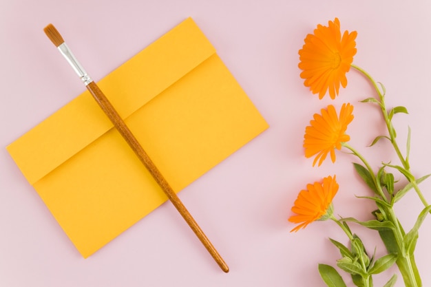 Vue de dessus des fleurs avec enveloppe et pinceau Photo gratuit