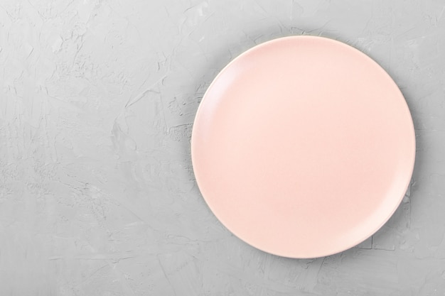 Vue de dessus de la plaque rose vide mate ronde sur l'espace de fond de ciment gris pour vous concevoir Photo Premium