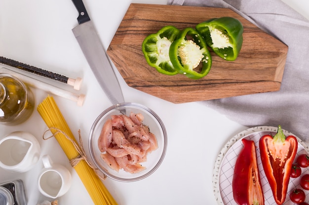 Une vue de dessus des poivrons; poulet en tranches; spaghettis sur fond blanc Photo gratuit