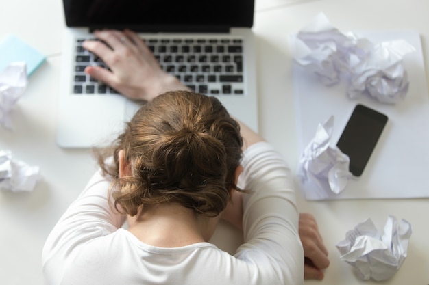 Vue de dessus portrait de femme allongée au bureau près de l'ordinateur portable Photo gratuit