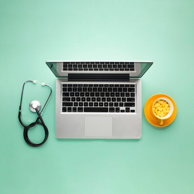 Vue dessus, de, tablettes, sur, tasse, à, ordinateur portable, et, stéthoscope, sur, bureau vert Photo gratuit