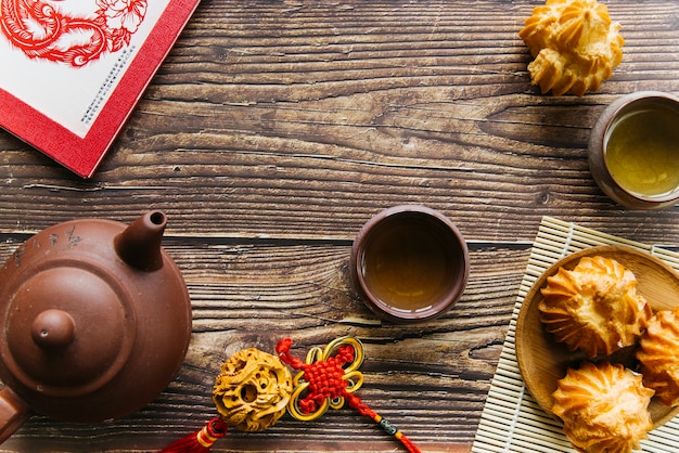 Une vue de dessus de la théière en argile et des tasses à thé avec des biscuits maison à la noix de coco sur la table en bois Photo gratuit