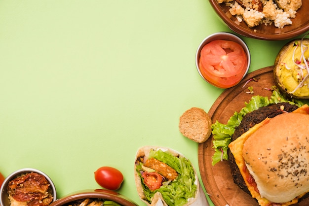 Une vue en élévation de la pellicule de burrito; salade et hamburger sur fond vert Photo gratuit