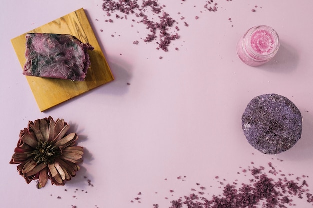 Une vue élevée du pain de savon; fleurs séchées et gommage corporel sur fond rose Photo gratuit