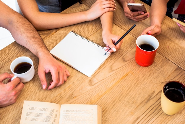 Vue élevée, de, étudiants, à, matériel étude, et, tasses de café, sur, table texturé bois Photo gratuit
