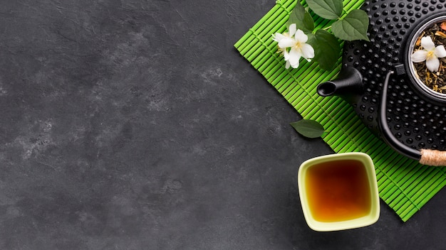 Vue élevée d'une tisane et de son ingrédient sur une surface texturée noire Photo gratuit