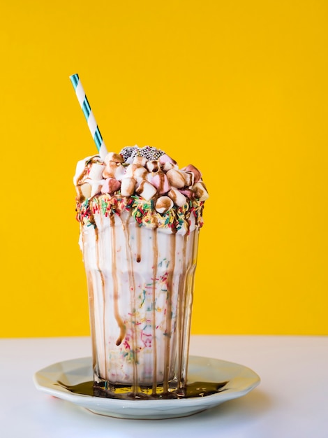 Vue de face de délicieux milkshake avec fond jaune Photo gratuit