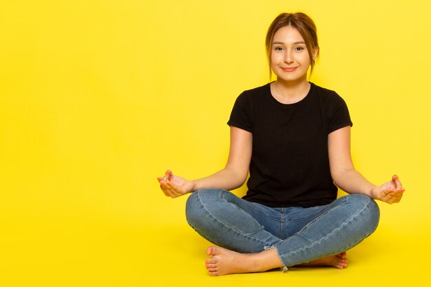 Une Vue De Face Jeune Femme Assise En Chemise Noire Et Jean Bleu