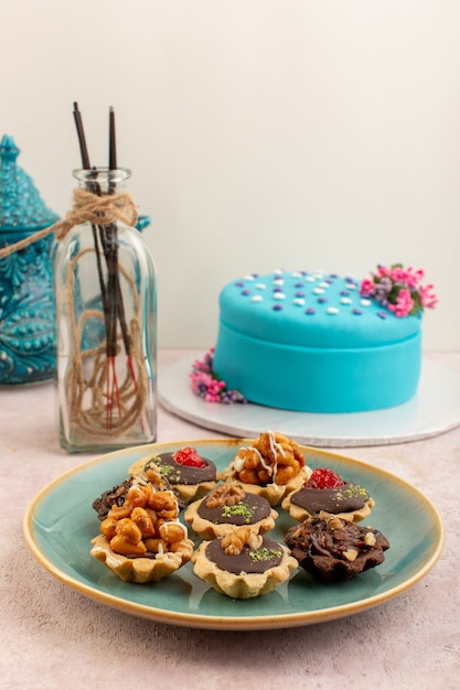 Une Vue De Face Petits Gateaux Au Chocolat A L Interieur De La Plaque Avec Gateau D Anniversaire Bleu Sur Le Bureau Rose Gateau Sucre Biscuit D Anniversaire Photo Gratuite