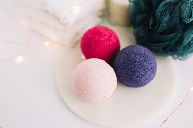 Vue grand angle des bombes de bain; luffa; serviette et guirlandes lumineuses sur une surface blanche Photo gratuit
