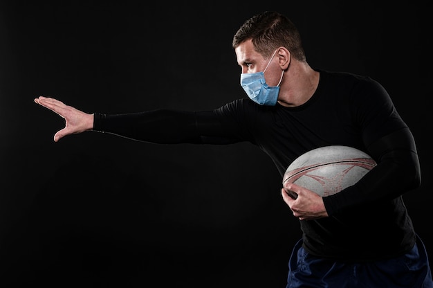 Vue Laterale Du Joueur De Rugby Masculin Avec Masque Medical Et Ballon Photo Gratuite