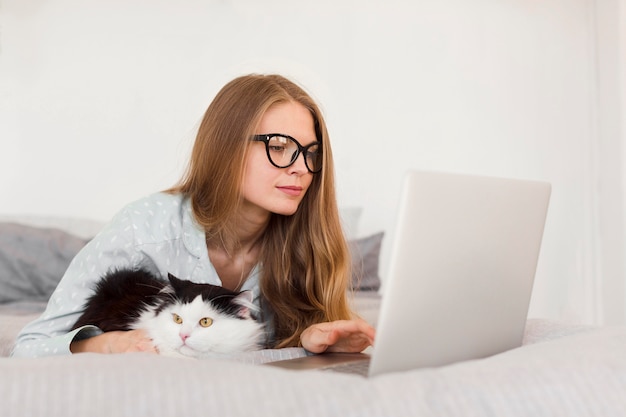 Vue Laterale D Une Femme Travaillant Sur Un Ordinateur Portable A La Maison En Pyjama Avec Chat Photo Gratuite