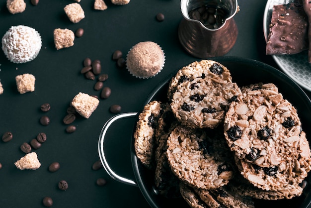 Une vue surélevée de biscuits dans les ustensiles et les grains de café sur fond noir Photo gratuit