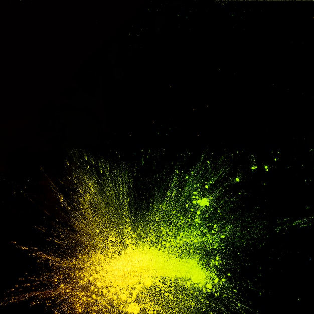 Vue surélevée d'explosion de poudre de couleur jaune sur fond noir Photo gratuit