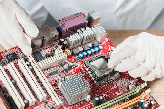 Vue surélevée d'un technicien travaillant sur une carte mère d'ordinateur Photo gratuit