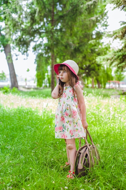 petite fille dans un parc de parler au telephone et avec un sac