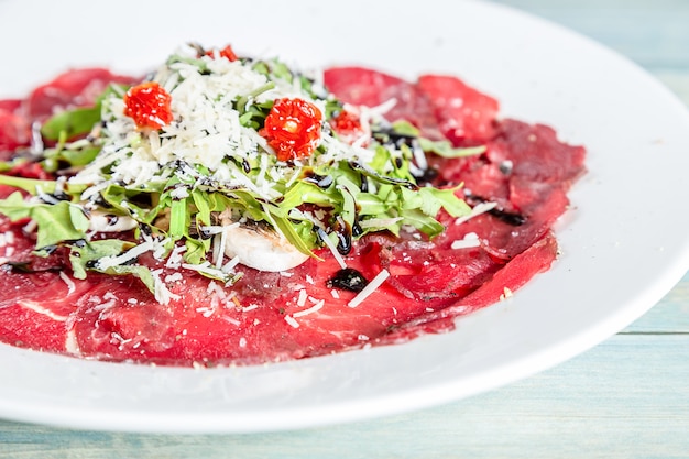 Carpaccio Di Manzo Con Rucola Parmigiano E Pomodori Secchi Foto Premium