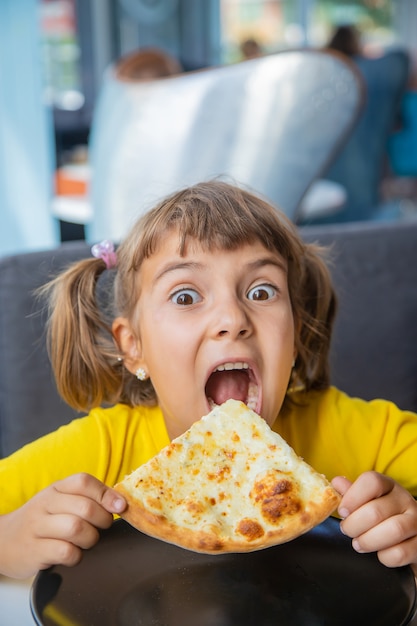 Il Bambino Mangia La Pizza Al Formaggio Foto Premium