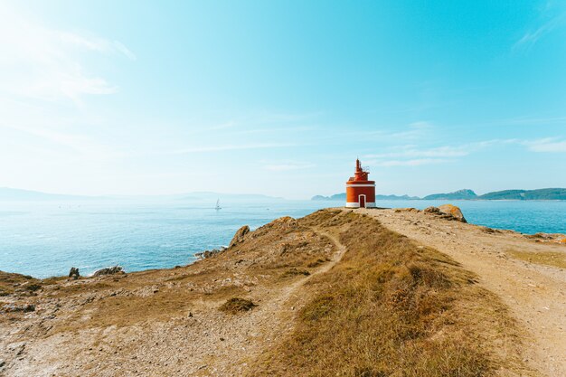 Un Colpo Colorato Di Un Faro Rosso Nella Parte Anteriore Dell Oceano Con Isole All Orizzonte Con Copia Spazio Foto Premium