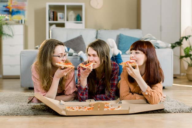 Mangiare fast food. felici tre bellissimi amici che ridono ...